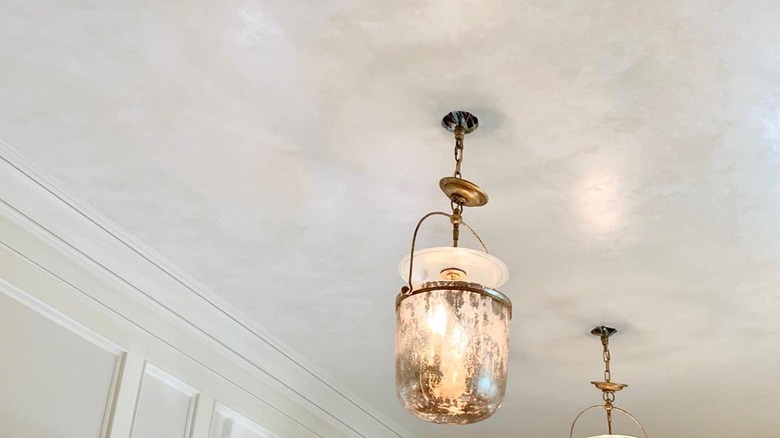 White ceiling glaze with hanging gold lighting fixture.