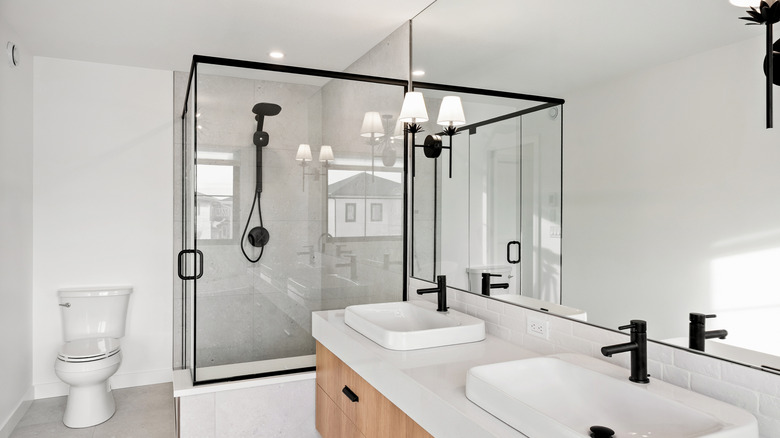 A white bathroom with black fixtures and a large shower.