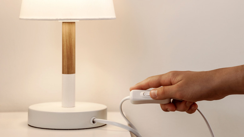 hand turning on lamp switch