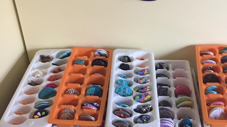 stack of orange and white ice cube trays filled with buttons