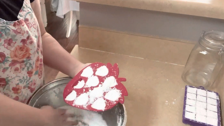 woman making white toilet bomb with red strawberry mold