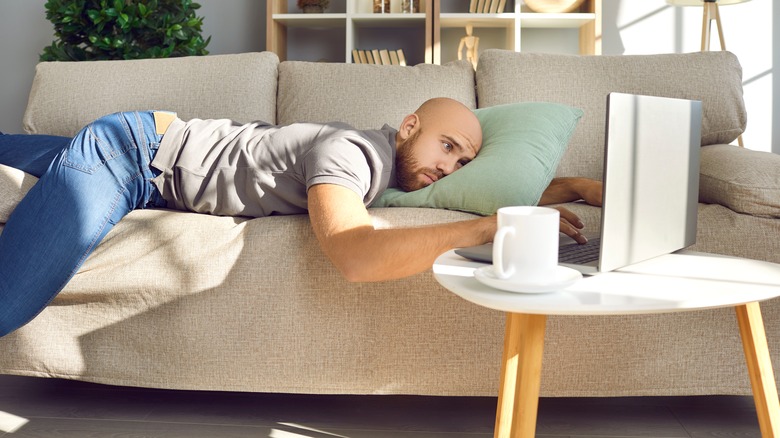 Man laying on couch typing