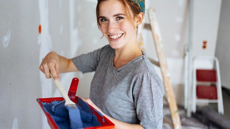 Woman smiling holding paint tray