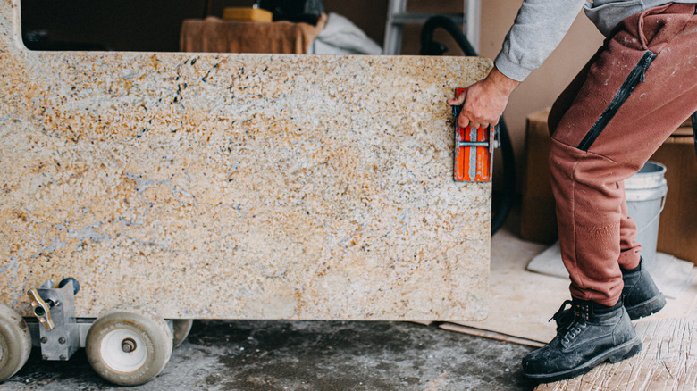 A person moving a piece of granite countertop
