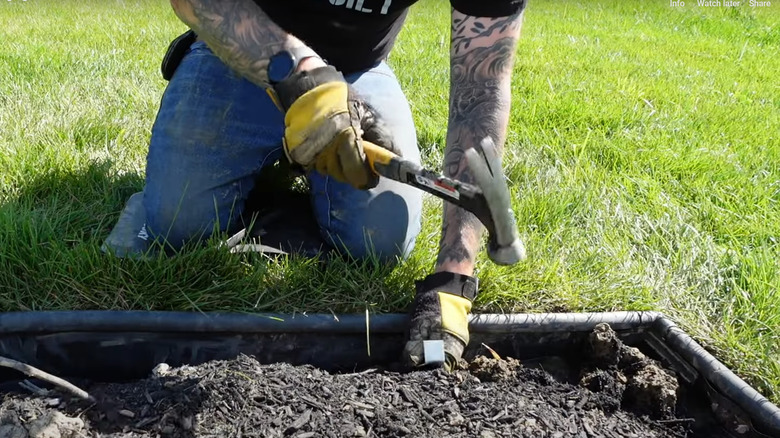 Man hammering heavy metal stakes into landscape edging