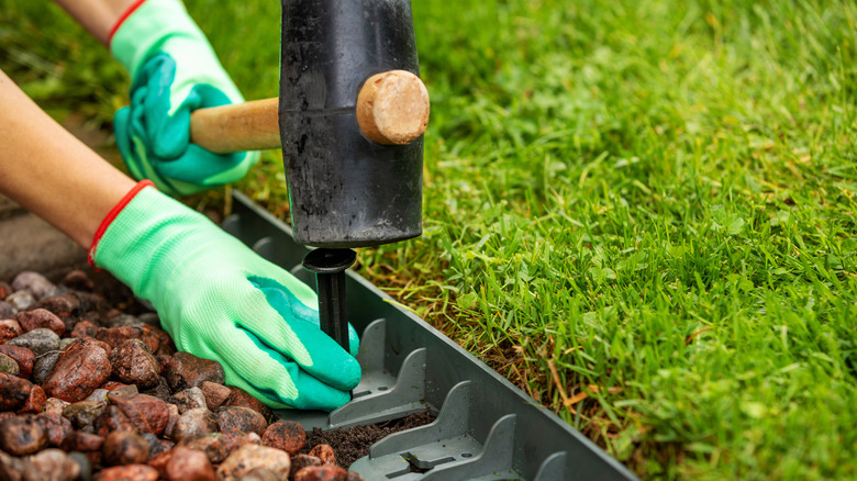 A person installing landscaping edging