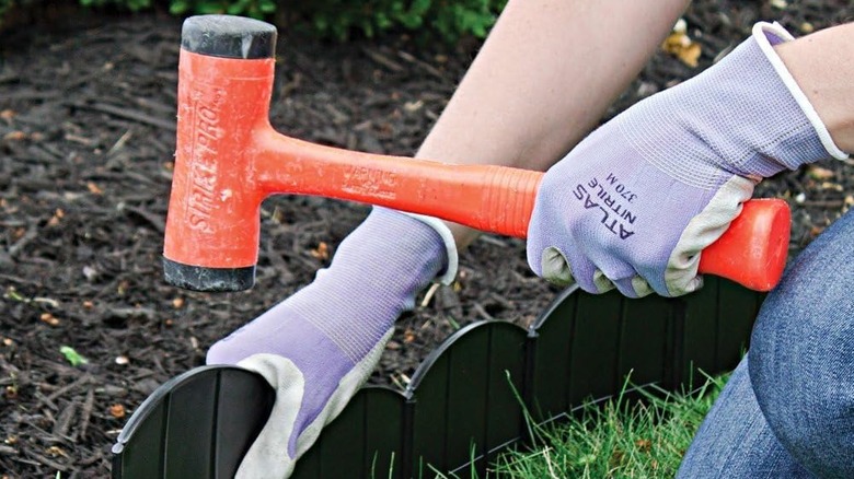 Woman using rubber mallet for plastic landscape edging