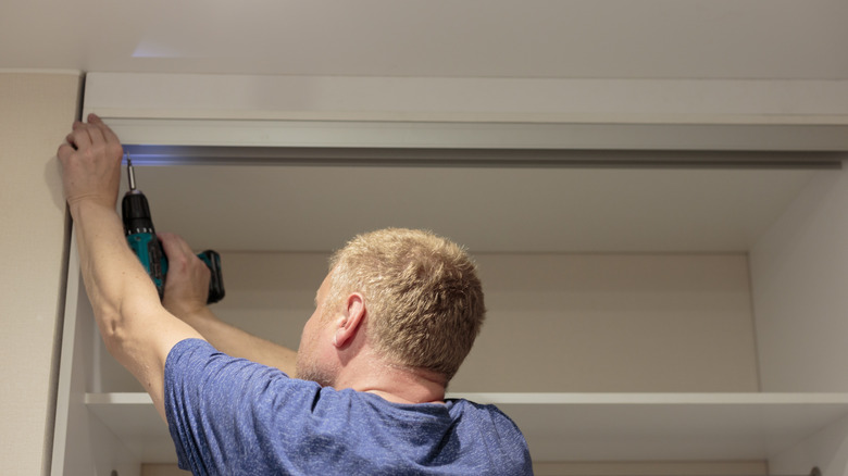Person installing the top track of a sliding closet door
