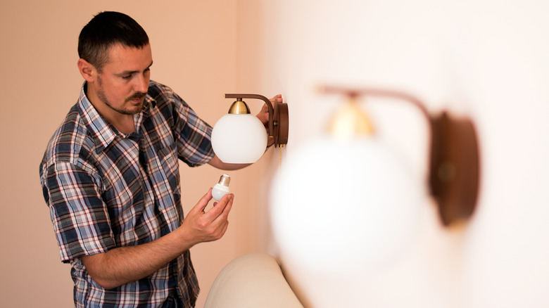 man installing wall sconce