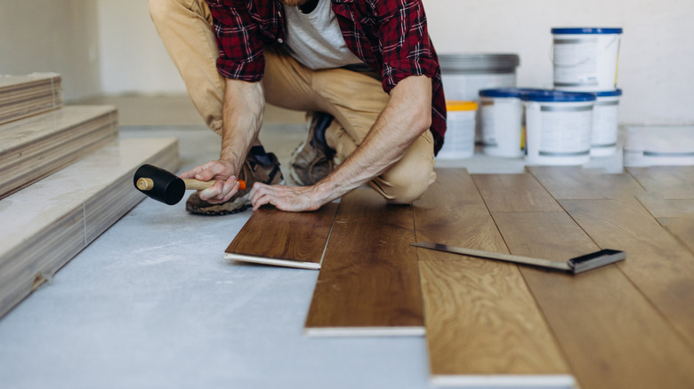 Man installing wide plank wood floors with a mallet