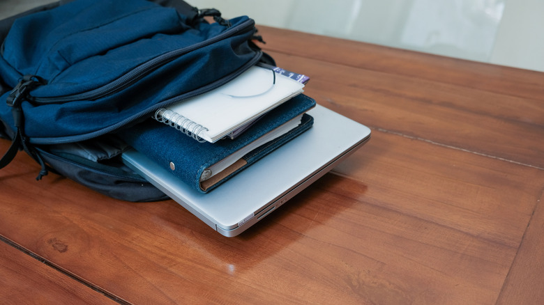 open backpack with books and laptop on coffee table