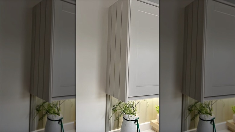 The end of a upper kitchen cabinet upgraded with wood panels and trim painted white.