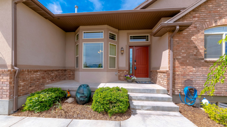 The exterior of a home features a big bay window and a transom window above the door