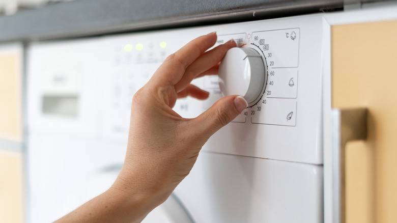 person adjusting washing machine settings