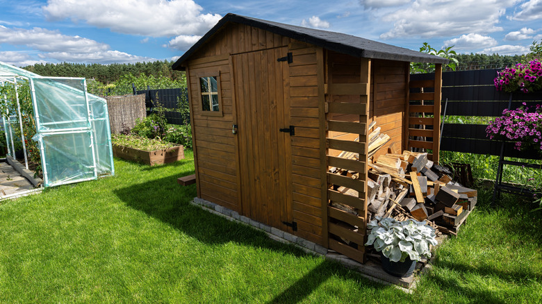 A sturdy multi-purpose wooden shed on a solid foundation sitting among garden beds