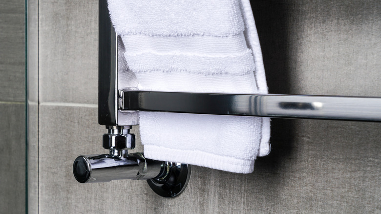 A stainless steel bathroom towel drying rack on a gray anthracite tile wall
