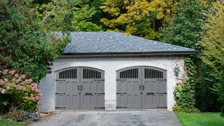 House surrounded by trees with grey hinged garage doors