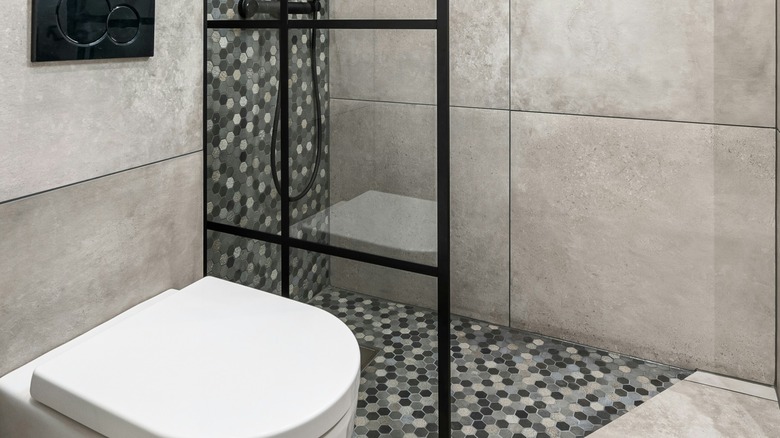 A bathroom with large format tiles on the wall, and mosaic hexagon tiles in the walk-in shower