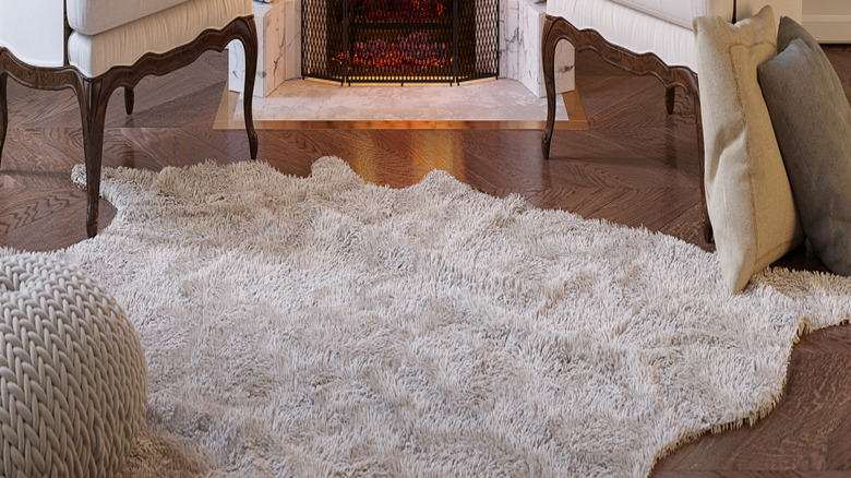 Armchairs flank a marble fireplace with fire.