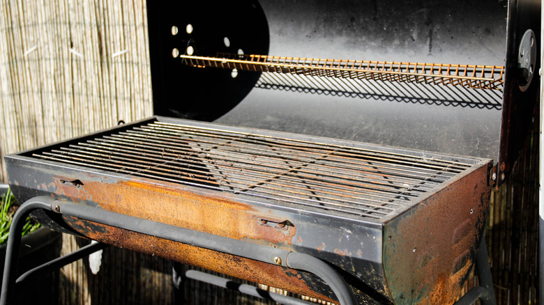 A run-down grill's hood opened to reveal rusty grates