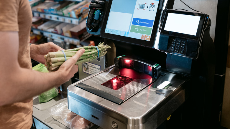person using self-checkout machine at grocery store