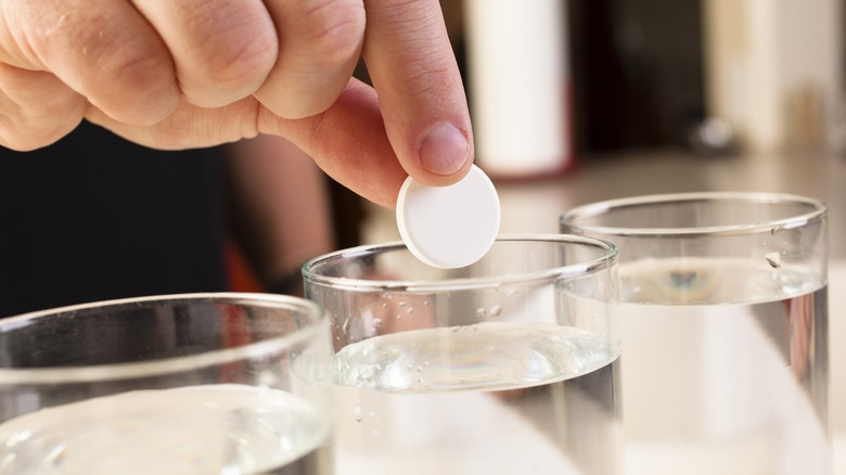 Person dropping Alka-Seltzer into a glass