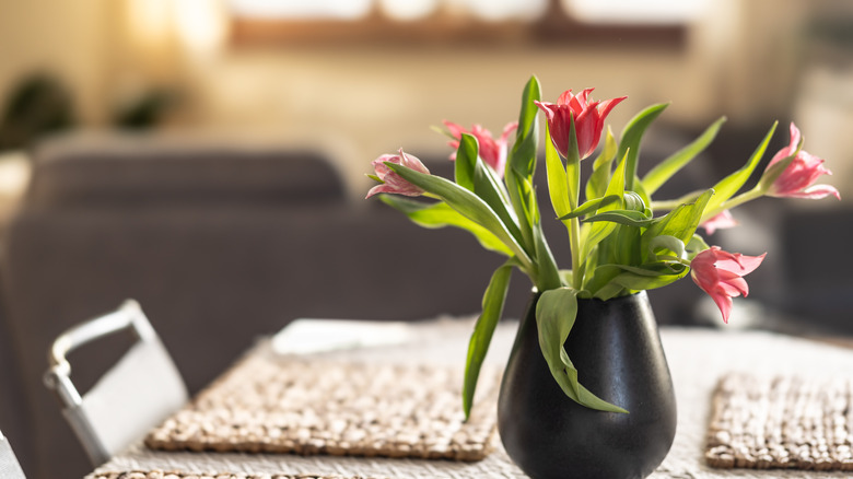 Tulips growing in a vase on a kitchen table.