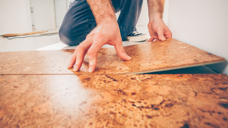 Hands laying cork floorboard