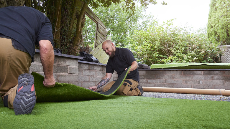Men installing artificial turf in a yard