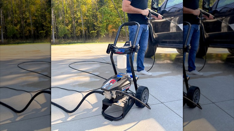 Man pressure washing a black car