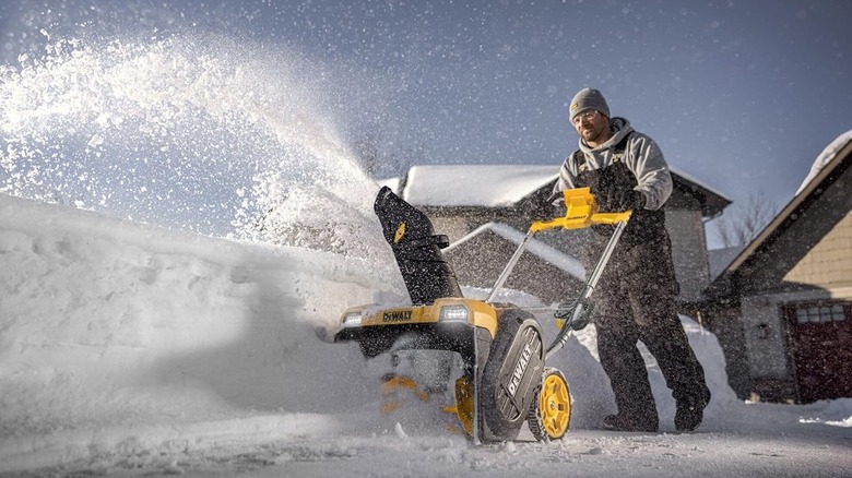 Man using a DeWalt snow blower near his home