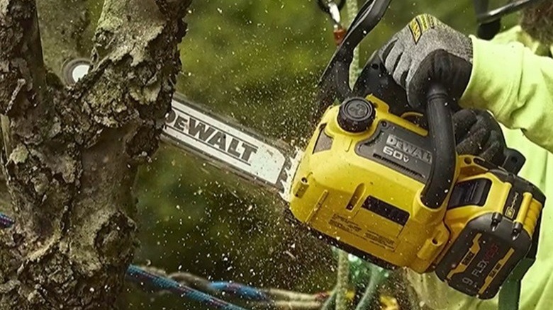 Person using DeWalt's 60V 12-inch chainsaw