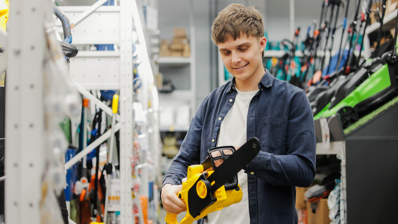 Man holding a DeWalt chainsaw in a store