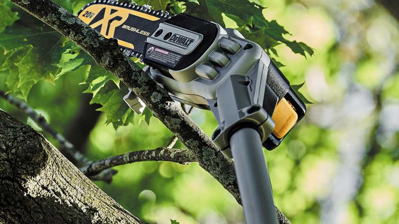 DeWalt battery pole saw cutting through a tree limb