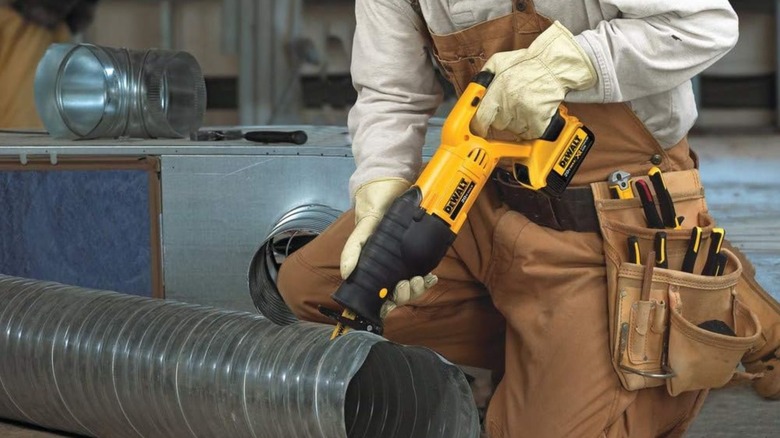 A person using a reciprocal saw to cut aluminum venting