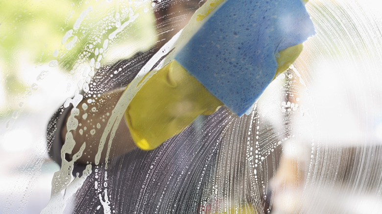 person cleaning windows with gloves and sponge 