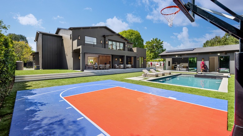 Basketball court in a backyard of a big house next to pool