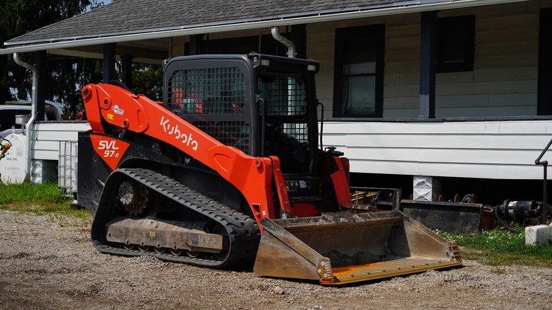 Skid loader leveling ground in a backyard next to house