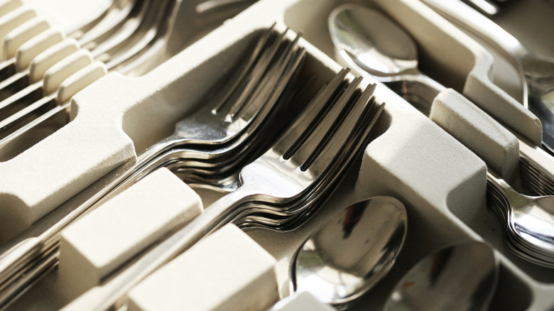 A tray of stainless steel flatware, including forks and spoons