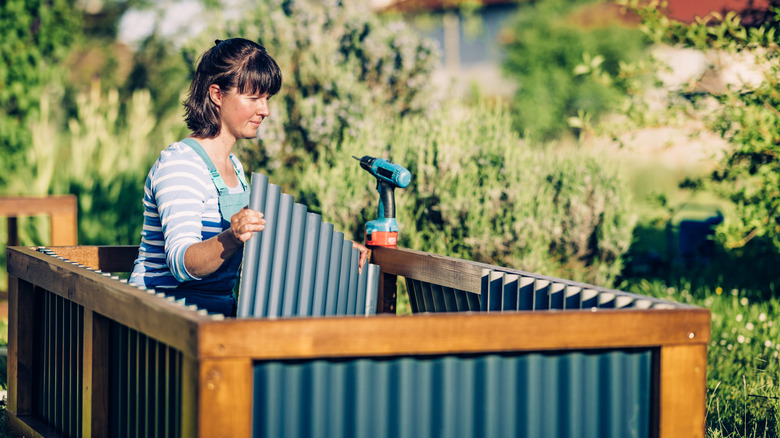 A gardener building a raised bed with galvanized metal panels