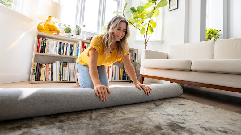 A happy woman putting down a rug