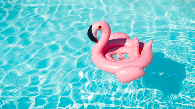 A pool filled with crystal clear water and a floating flamingo inflatable.