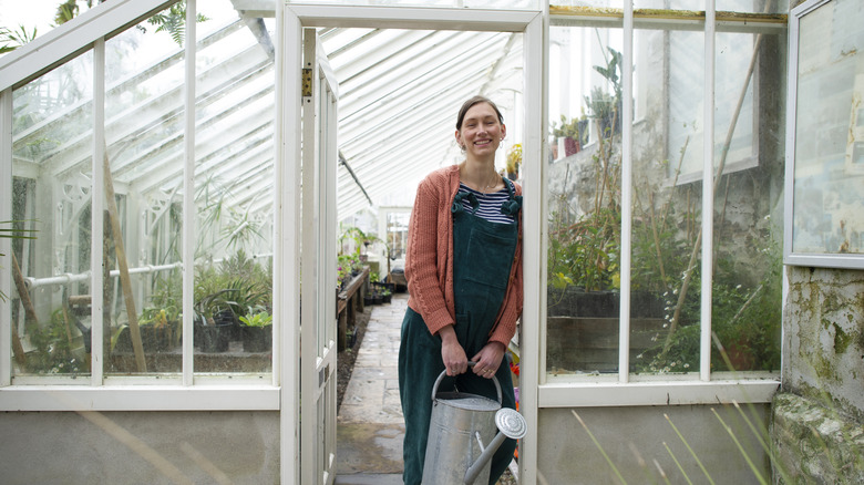 A woman smiling in from of her greenhouse
