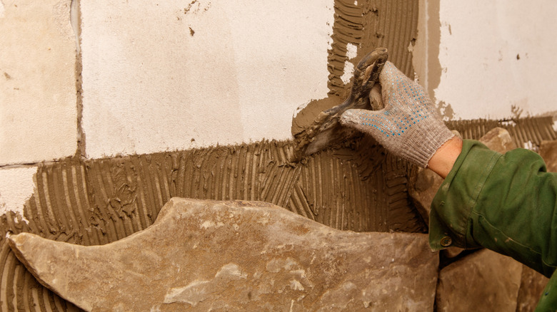 An artisan is applying a mortar or plaster to walls.