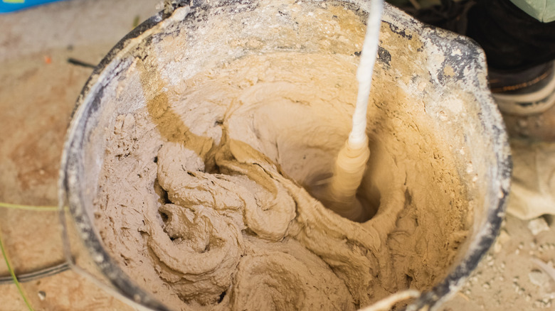 White plaster is being mixed in a large bucket.