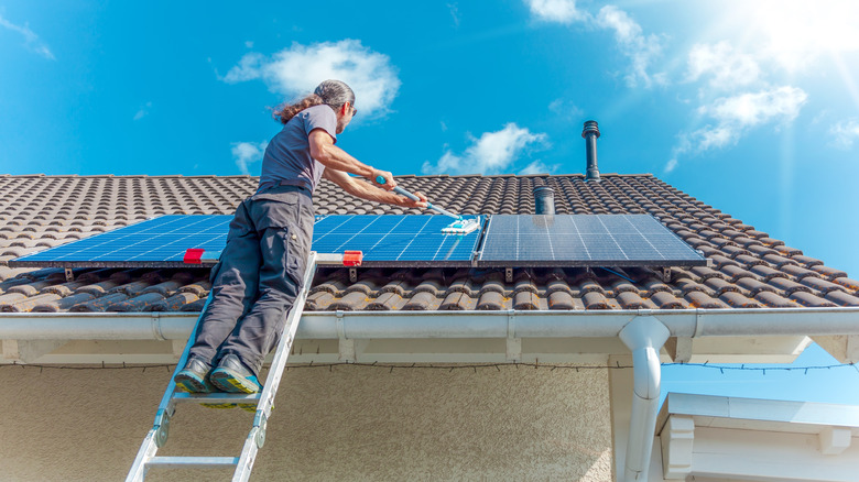 A man cleaning solar panels with a mop