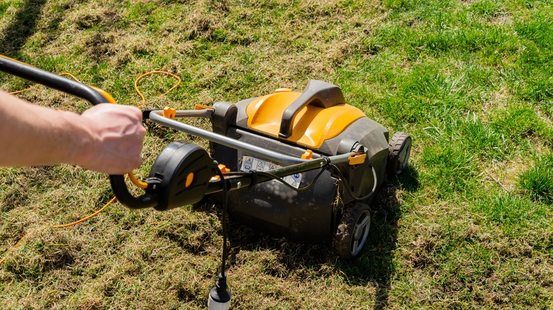 Man pushing grass aerator