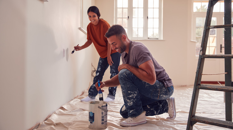 couple painting wall of home