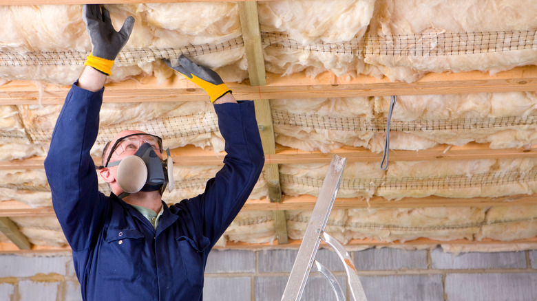 man examining basement ceiling insulation