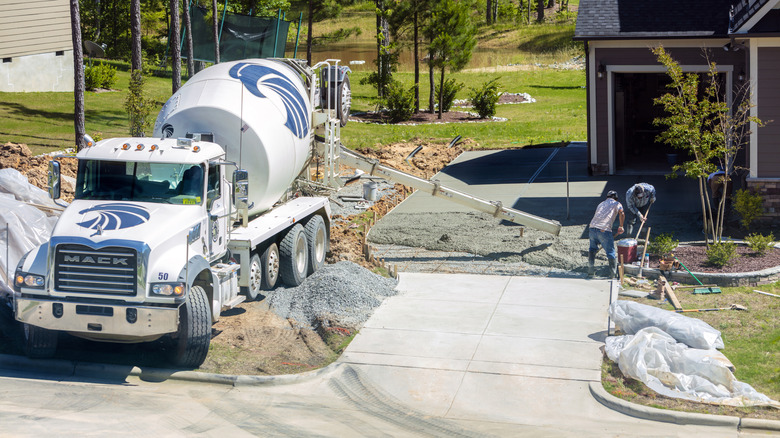 Workers laying a concrete driveway with a cement truck